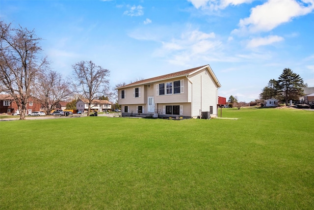 rear view of property with central AC and a lawn