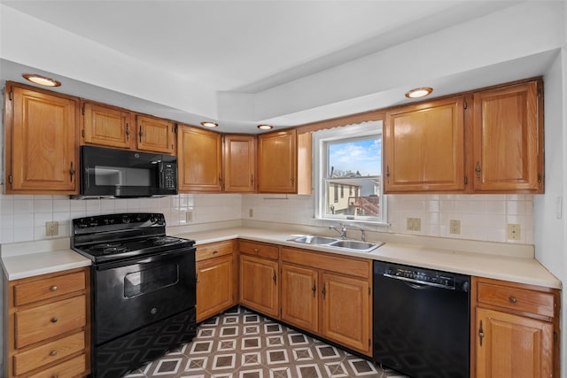 kitchen with backsplash, light countertops, a sink, and black appliances