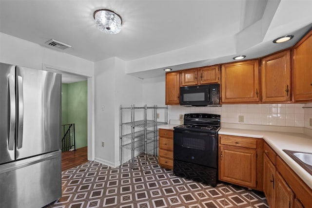 kitchen featuring light countertops, visible vents, black appliances, and decorative backsplash