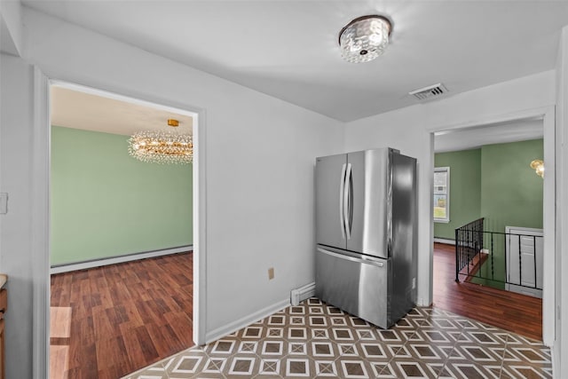 kitchen featuring visible vents, a baseboard heating unit, an inviting chandelier, and freestanding refrigerator