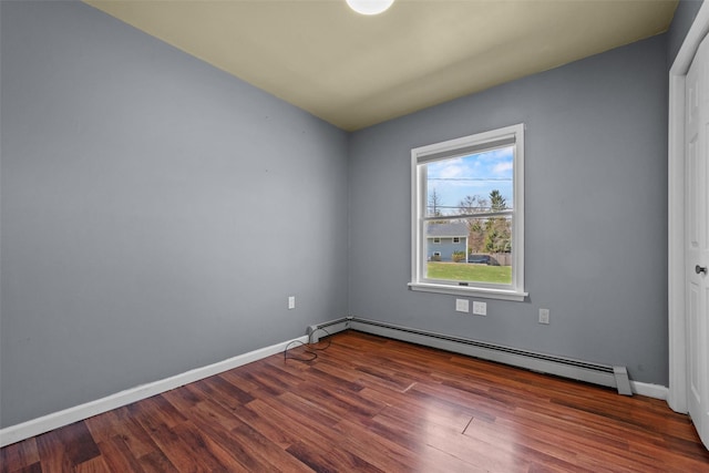spare room with wood finished floors, baseboards, and baseboard heating