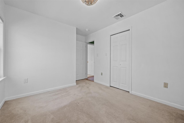 unfurnished bedroom with a closet, carpet, baseboards, and visible vents