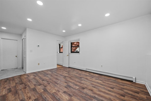 spare room featuring wood finished floors, baseboard heating, baseboards, and recessed lighting