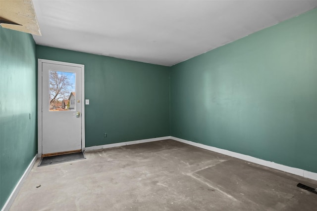 empty room with concrete flooring and baseboards