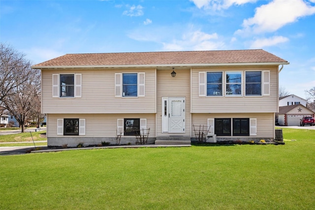 bi-level home with cooling unit, a front yard, and a shingled roof