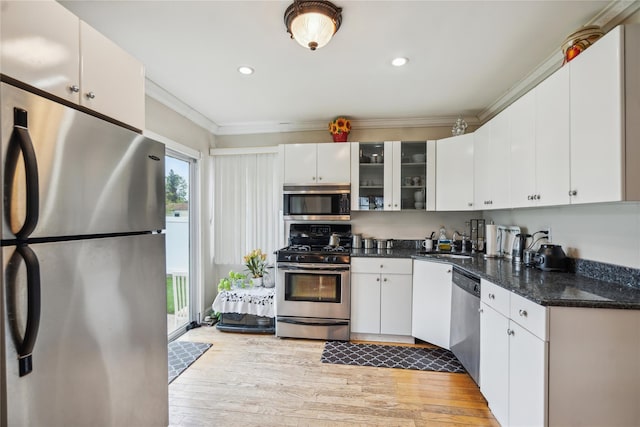 kitchen with stainless steel appliances, a sink, light wood finished floors, crown molding, and glass insert cabinets