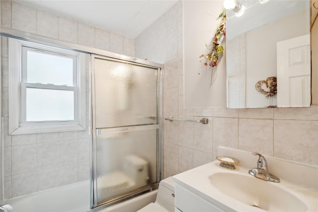 full bath featuring combined bath / shower with glass door, vanity, and tile walls