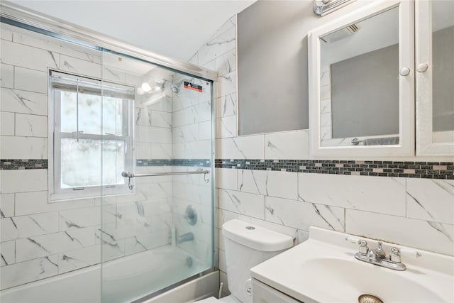 bathroom featuring tile walls, bath / shower combo with glass door, toilet, and vanity