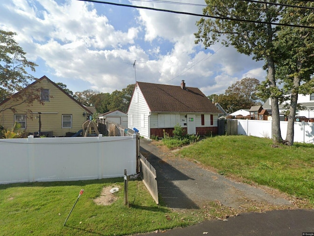 view of side of home featuring a lawn and fence