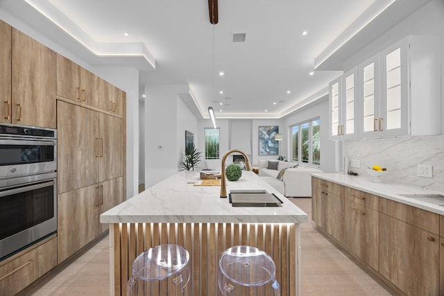 kitchen featuring visible vents, modern cabinets, a sink, and light stone counters