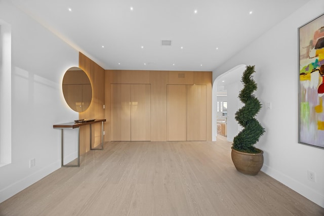 hall featuring light wood finished floors, baseboards, and visible vents