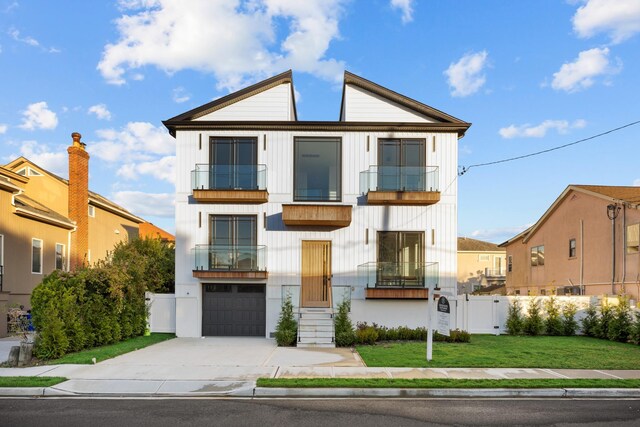 view of front of home with concrete driveway, fence, a balcony, a front lawn, and a garage