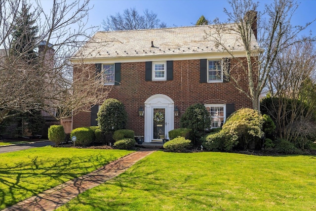colonial home featuring brick siding and a front yard