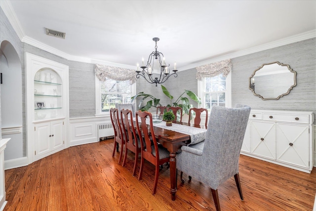 dining space featuring radiator heating unit, arched walkways, a notable chandelier, and a healthy amount of sunlight