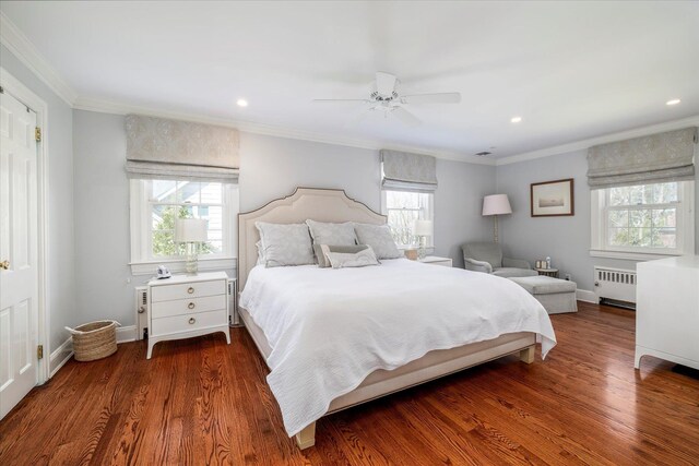 bedroom with radiator heating unit, wood finished floors, crown molding, and multiple windows