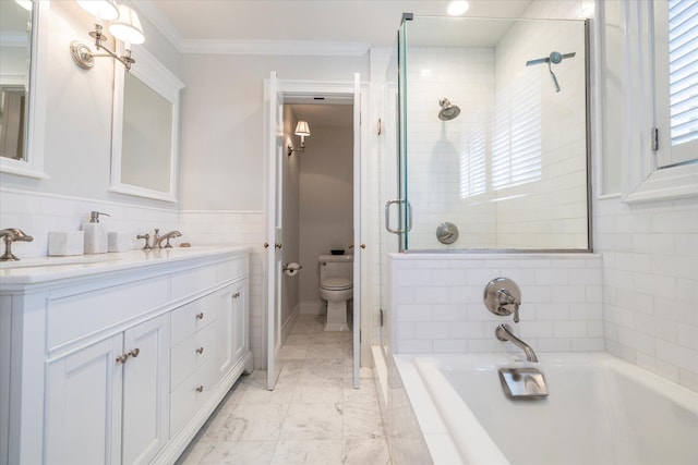 bathroom with double vanity, toilet, a sink, tile walls, and crown molding