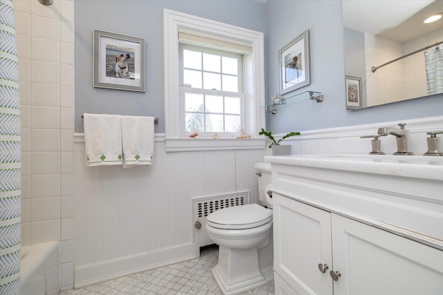 bathroom with radiator, toilet, vanity, wainscoting, and shower / tub combo