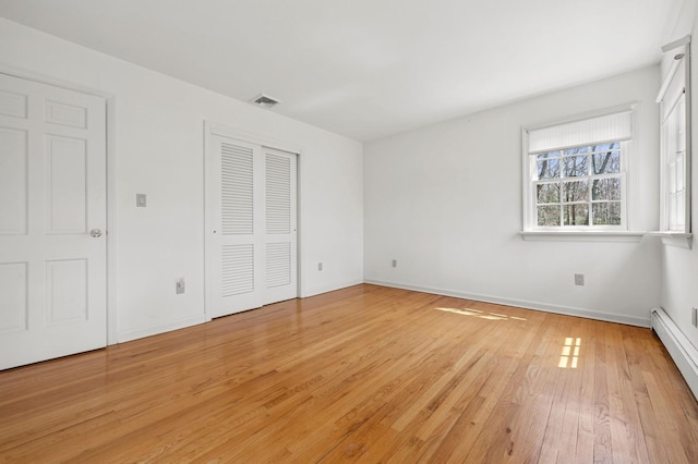 22 Druid Hill Rd, Port Jefferson, NY 11777 - unfurnished bedroom with baseboard heating, light wood-style flooring, a closet, and baseboards