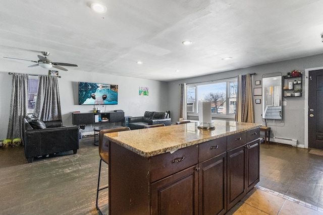 kitchen with light stone countertops, dark brown cabinets, recessed lighting, a breakfast bar, and a center island