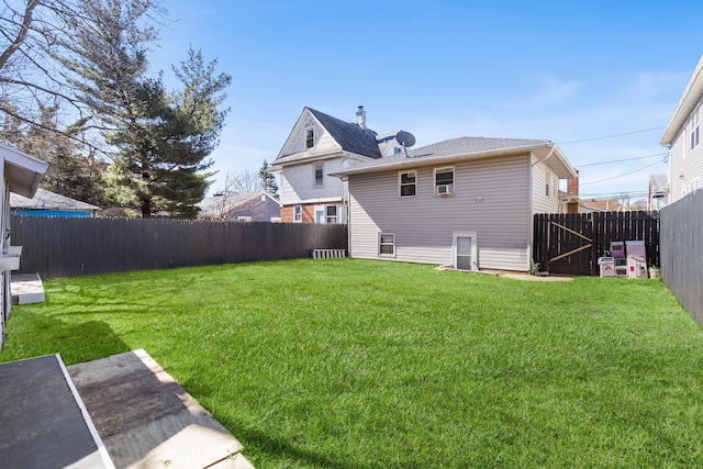 back of property with a fenced backyard and a lawn