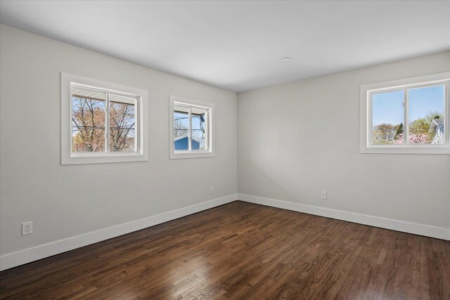 unfurnished room with dark wood-style flooring and baseboards