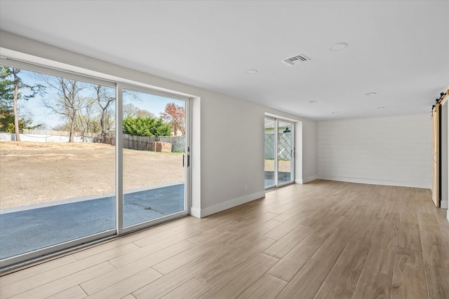 interior space with a barn door, wood finished floors, and plenty of natural light