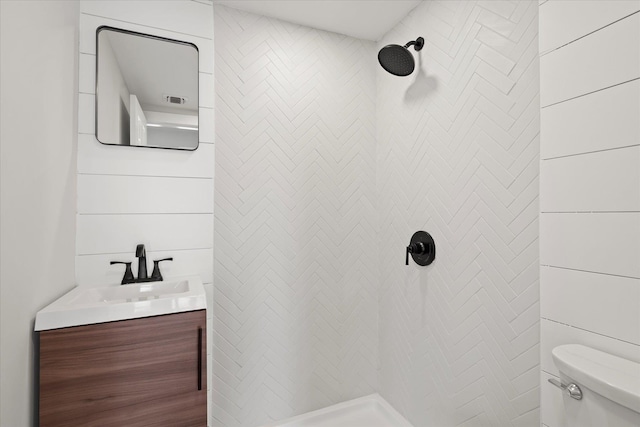 bathroom featuring toilet, a tile shower, and vanity