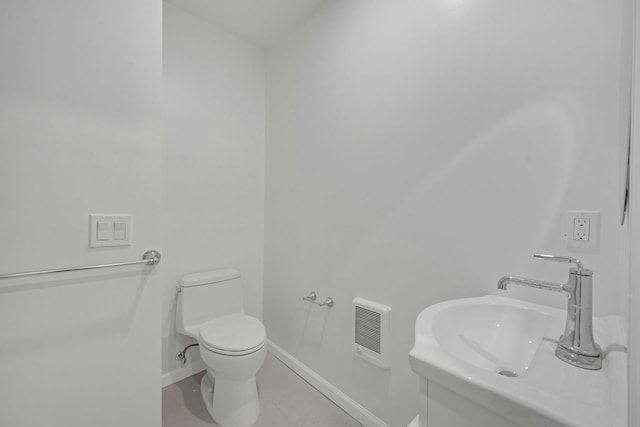 bathroom with baseboards, toilet, and a sink