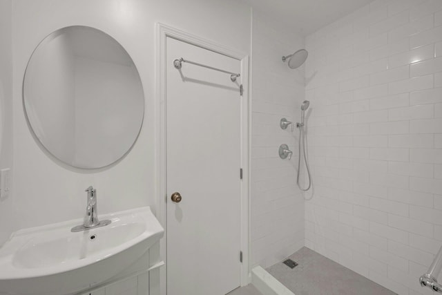 bathroom with tiled shower and a sink