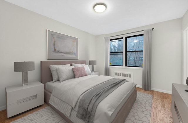 bedroom with radiator, baseboards, and light wood-style flooring