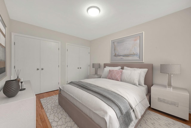 bedroom featuring multiple closets and light wood finished floors