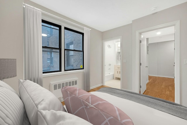 bedroom featuring radiator, baseboards, ensuite bathroom, and light wood-type flooring
