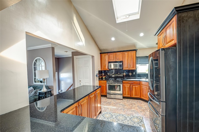 2892 Wilson Ave, Bellmore, NY 11710 - kitchen with lofted ceiling with skylight, dark stone countertops, backsplash, appliances with stainless steel finishes, and brown cabinets
