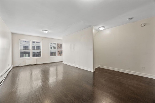 unfurnished room featuring baseboards, baseboard heating, and wood finished floors