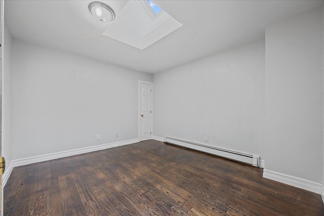 spare room with baseboards, dark wood finished floors, a skylight, and a baseboard radiator