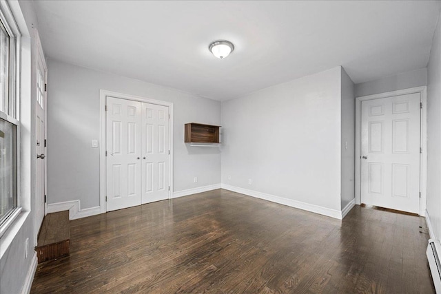 unfurnished room featuring dark wood finished floors, a baseboard radiator, and baseboards