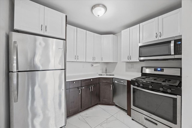 kitchen with light countertops, stainless steel appliances, marble finish floor, a sink, and dark brown cabinetry