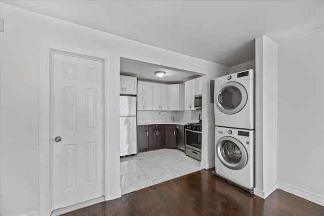clothes washing area featuring marble finish floor, baseboards, laundry area, and stacked washer / drying machine