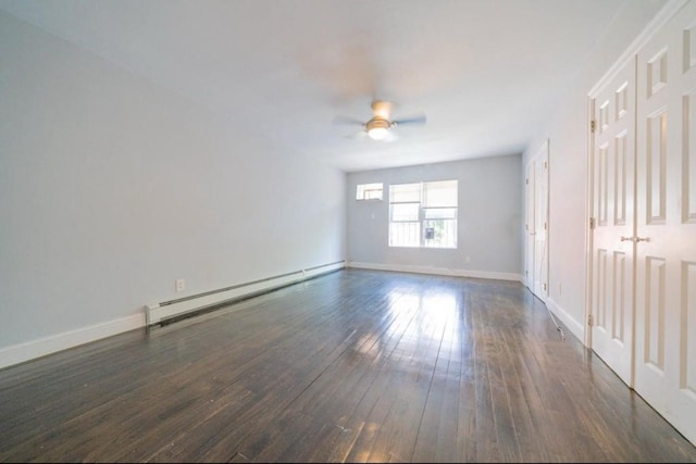 empty room featuring baseboards, ceiling fan, a baseboard heating unit, and dark wood finished floors