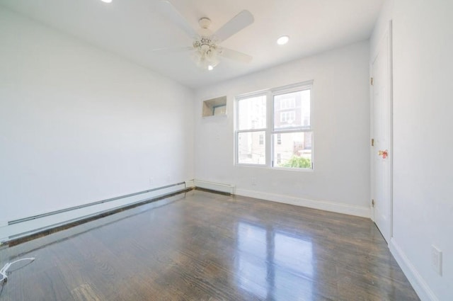 spare room featuring a baseboard radiator, a ceiling fan, baseboards, and wood finished floors