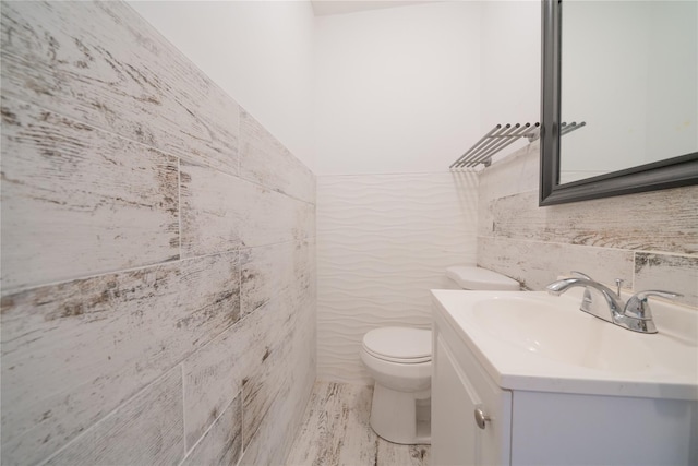 bathroom featuring tile walls, toilet, and vanity