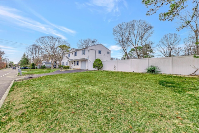 view of yard featuring aphalt driveway and fence