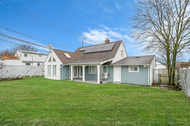173 Bloomingdale Rd, Levittown, NY 11756 - back of property featuring roof mounted solar panels, a yard, a fenced backyard, a patio area, and a shingled roof