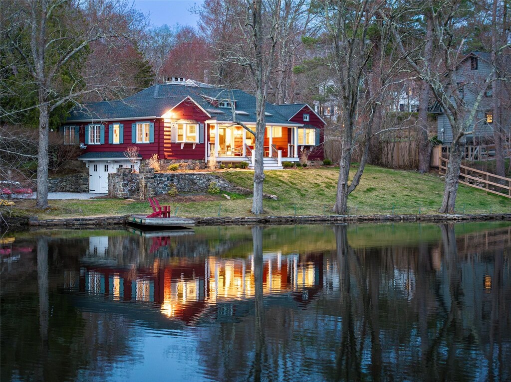 rear view of property featuring a water view, a shingled roof, and a yard