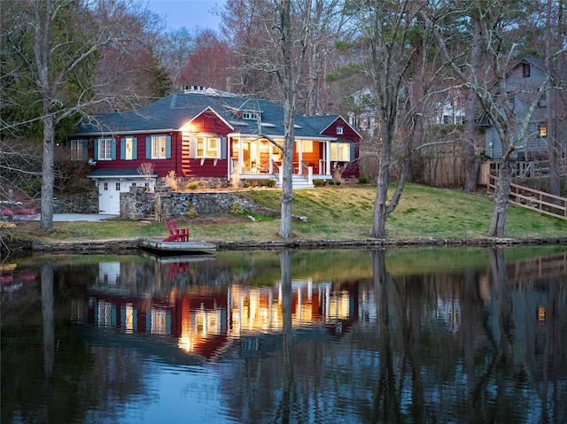 rear view of property featuring a water view, a shingled roof, and a yard