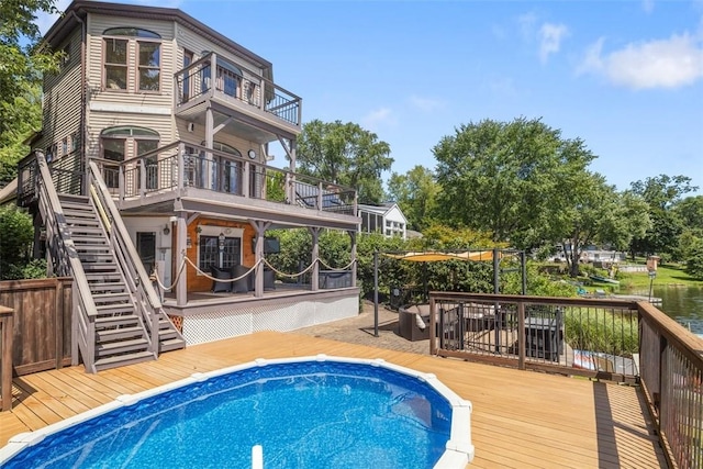 545 Shore Dr, New Windsor, NY 12553 - rear view of house featuring a balcony, a deck with water view, stairway, and an outdoor pool