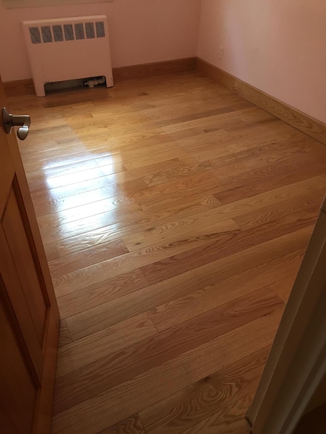 2443 Bouck Ave, Bronx, NY 10469 - unfurnished room with baseboards, light wood-style flooring, and radiator heating unit