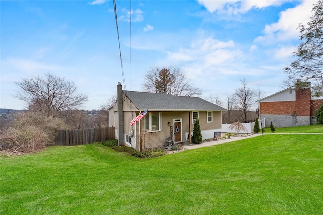 rear view of house featuring fence, a lawn, and a chimney