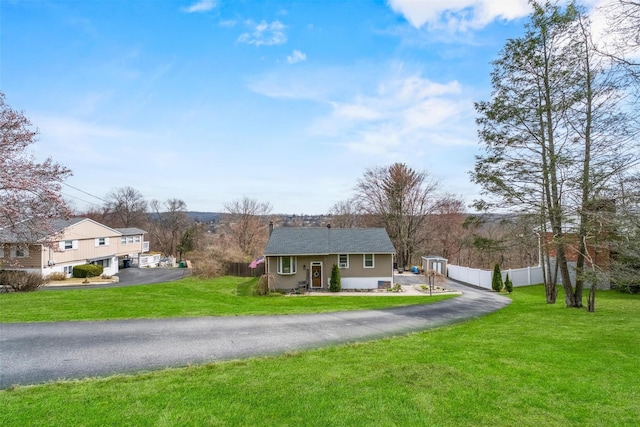 view of front facade featuring fence, a front lawn, and aphalt driveway