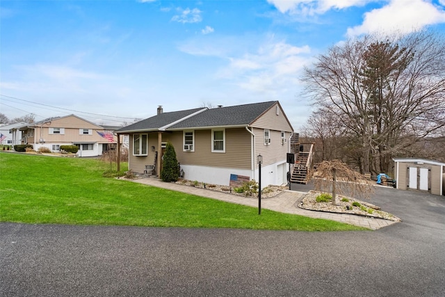 view of front of house featuring a storage shed, driveway, a garage, stairway, and a front yard